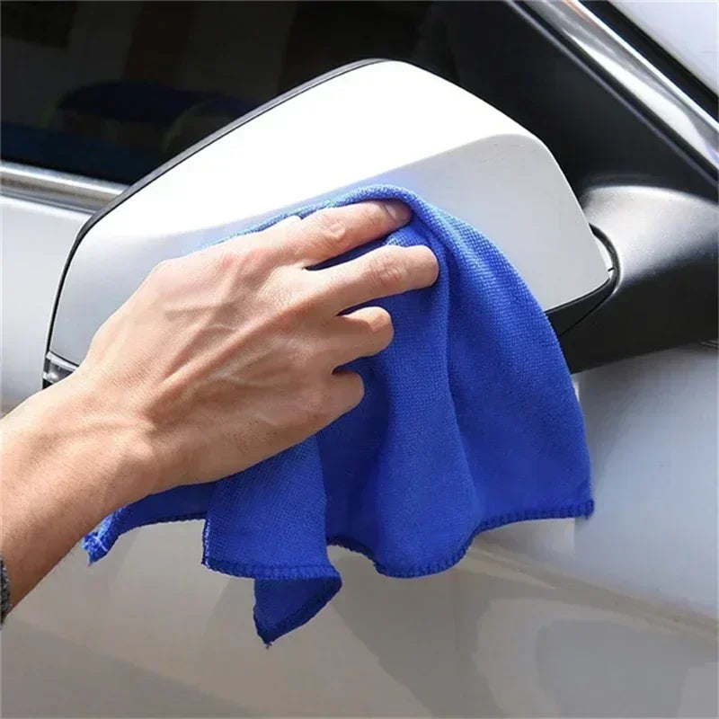 Person cleaning a car mirror with a blue microfiber cloth