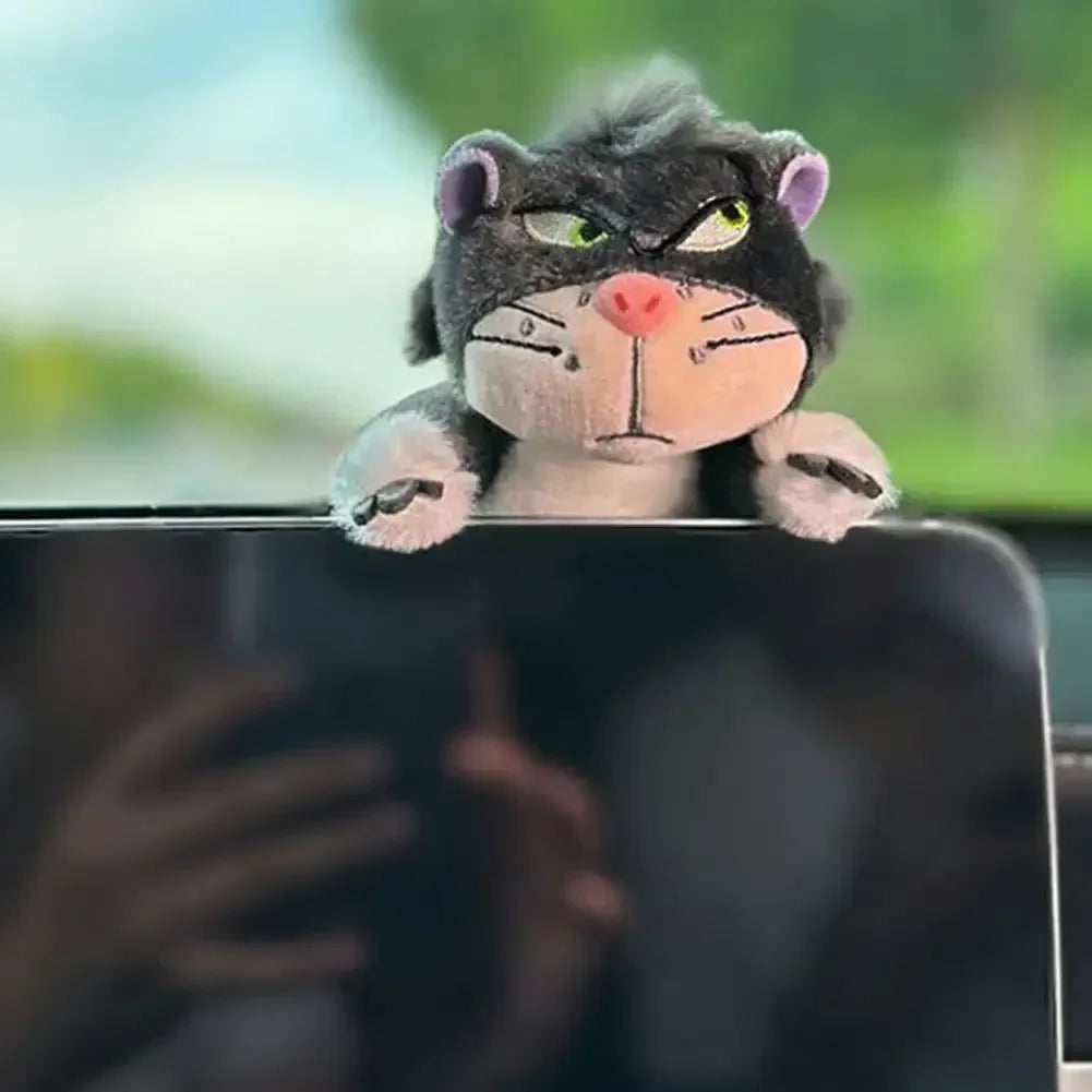 Gray cat plush toy resting on top of a car dashboard screen as a cute interior decoration