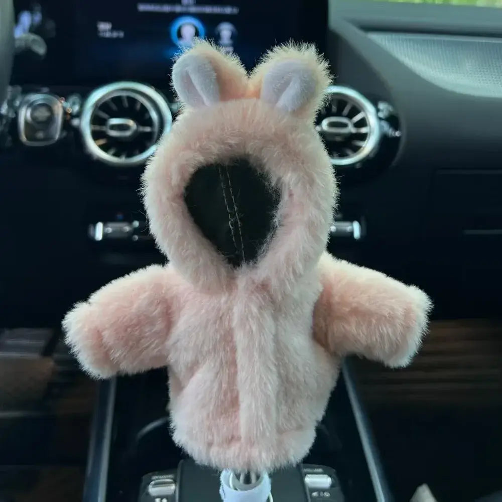 Cute pink rabbit cartoon plush gear shift cover installed on gear lever in Mercedes interior with small ears outstretched arms and soft pink plush body