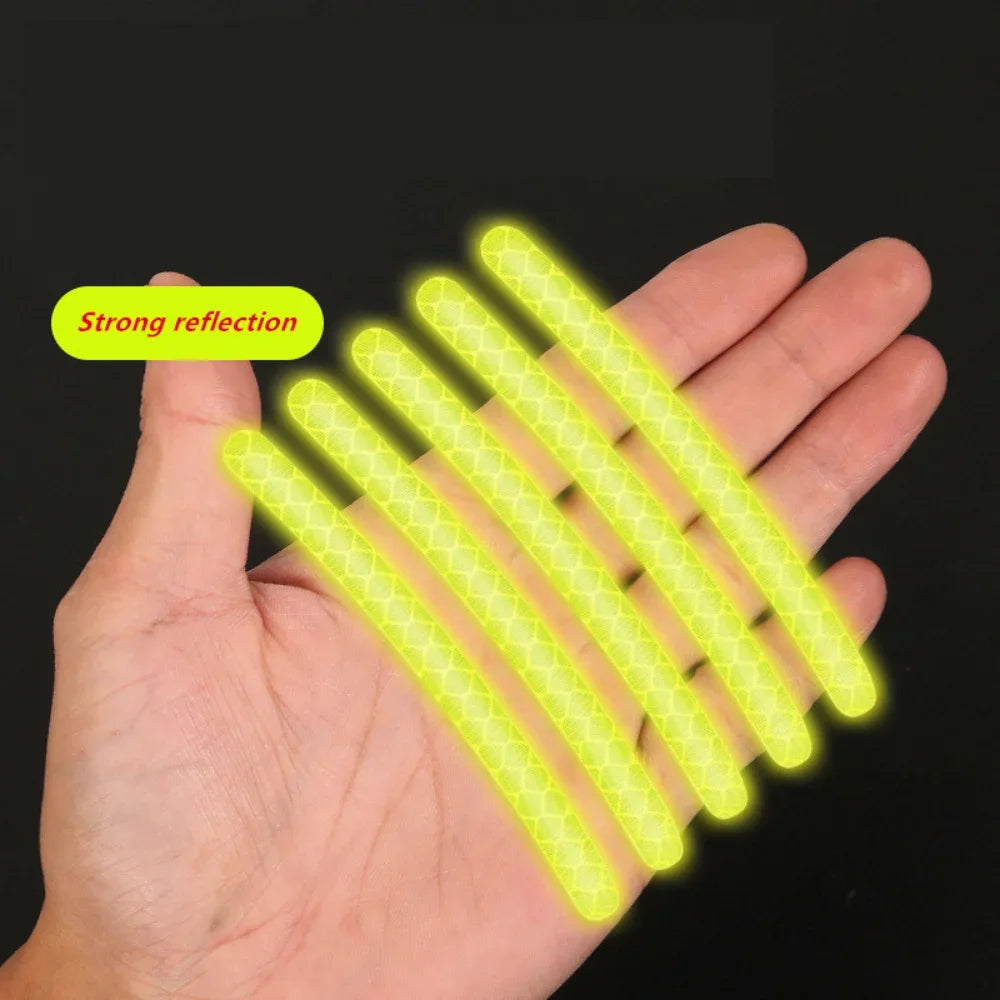 Hand holding green reflective rim decals showcasing strong night visibility and compact size
