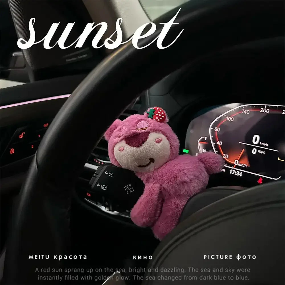 Pink bear plush toy clipped on car dashboard stalk with sunset aesthetic and glowing speedometer