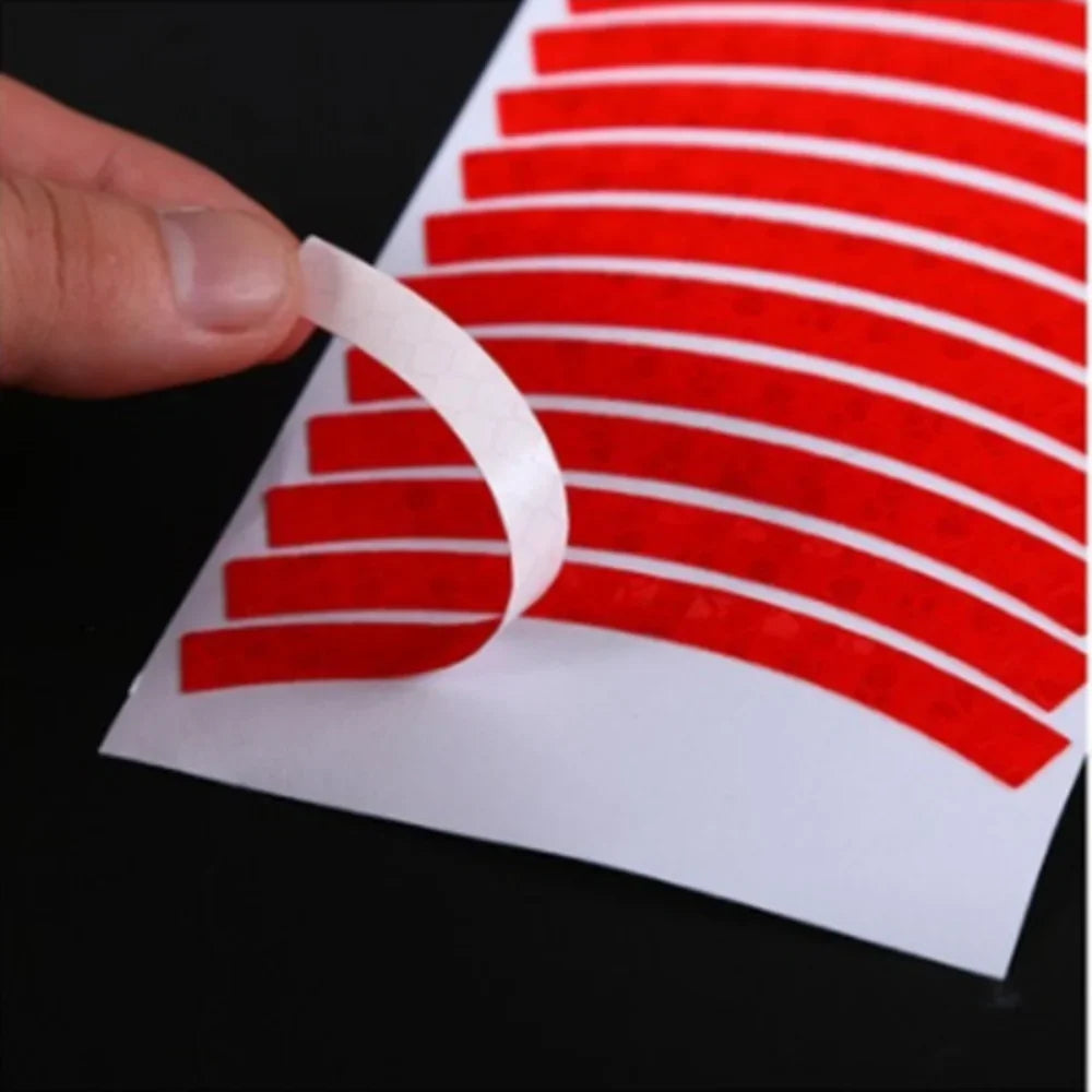 Peeling a red reflective wheel stripe from its adhesive backing sheet to show easy application