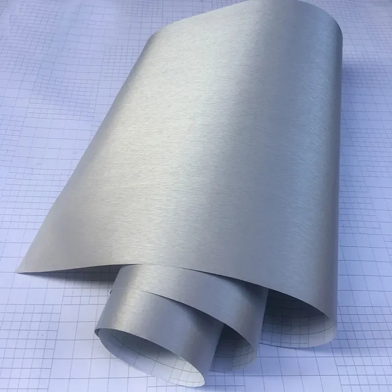 Silver brushed aluminum vinyl wrap roll unrolled on grid background