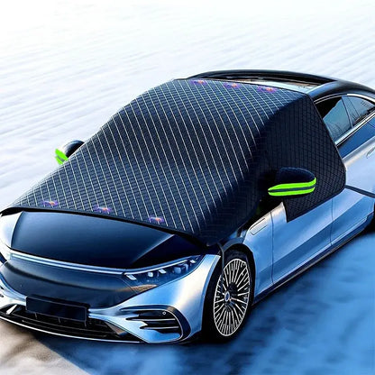 3-layer Oxford windshield cover installed on silver sedan in snowy winter scene with green reflective mirror covers and 6-magnet secure grip