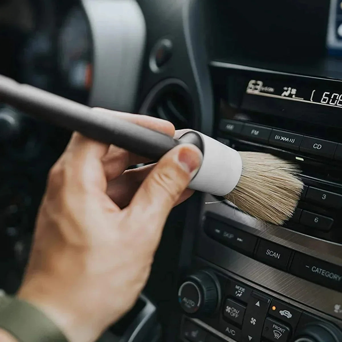 Car detailing brush cleaning interior dashboard and air vents