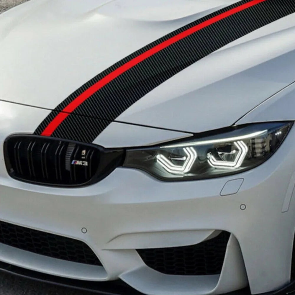 Close-up of carbon fiber and red racing stripe decal running across white BMW M3 hood towards grille