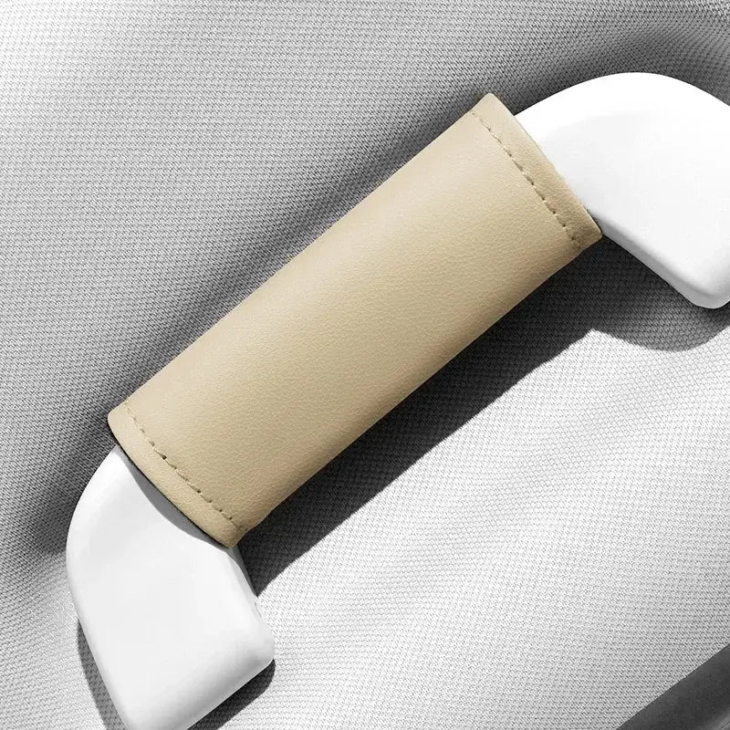 Single beige leather-look car roof handle cover installed on grab handle, close-up product shot