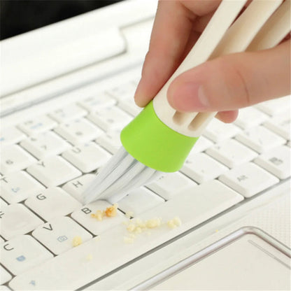 Bristle end of car vent brush sweeping crumbs from laptop keyboard keys