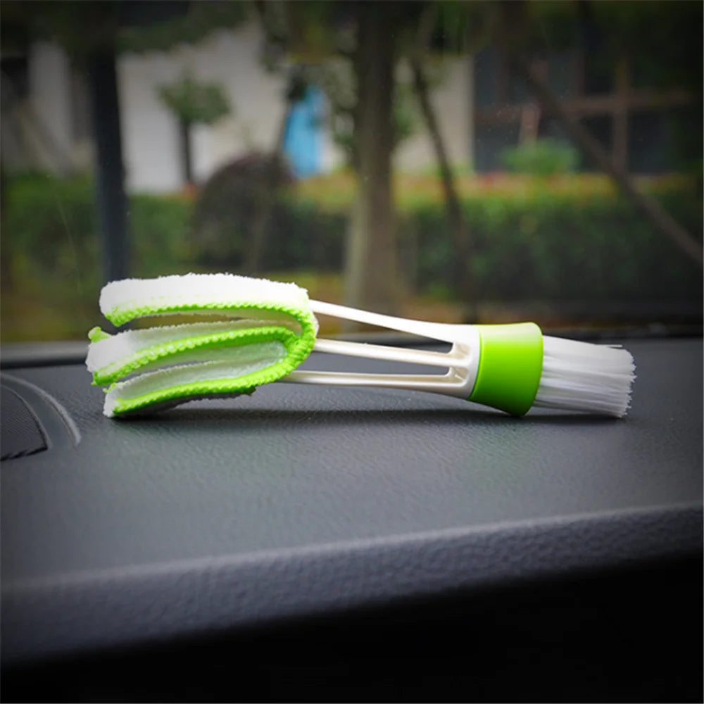 Double-ended car vent cleaning brush resting at angle on dark car dashboard