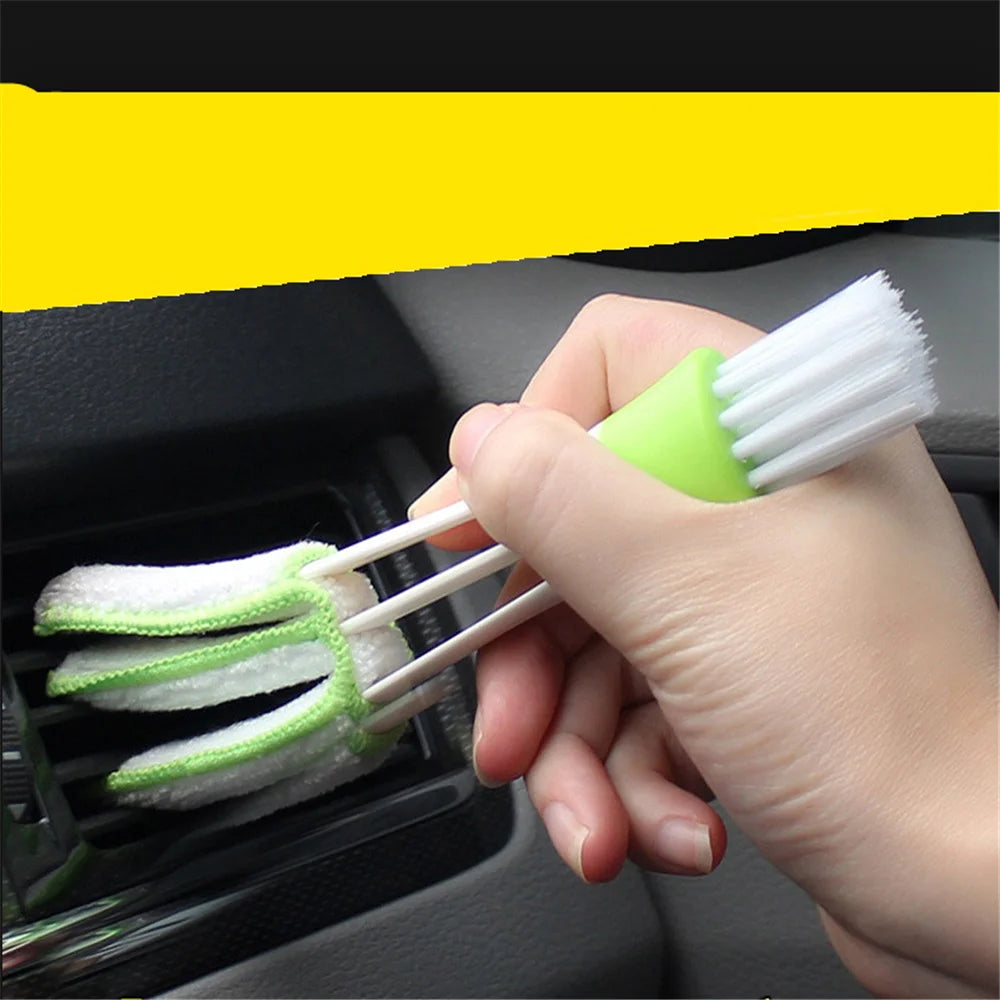 Hand inserting double-ended brush into car A/C vent showing bristle and microfiber ends in use