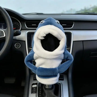 Cute blue shark cartoon plush gear shift cover installed on automatic gear lever in car interior with open mouth fin arms and googly eyes design