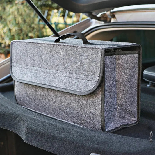 Light gray soft felt car trunk organizer with carry handle sitting on open trunk edge