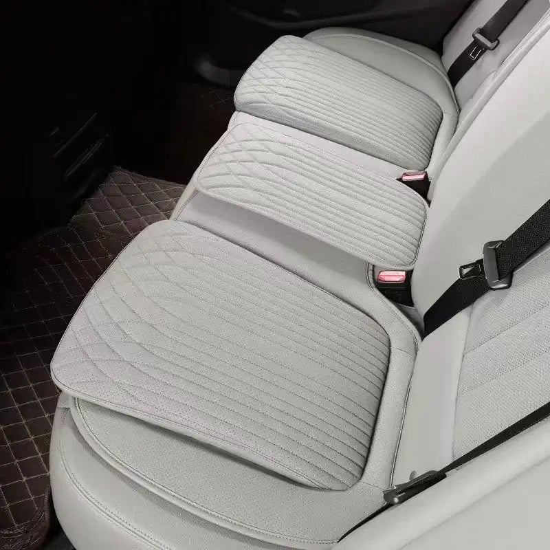 Beige leather car seat height cushion installed on rear seat showing thick padded profile and perforated surface
