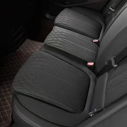 Black leather car seat height cushion installed on rear seat showing thick padded profile and perforated surface