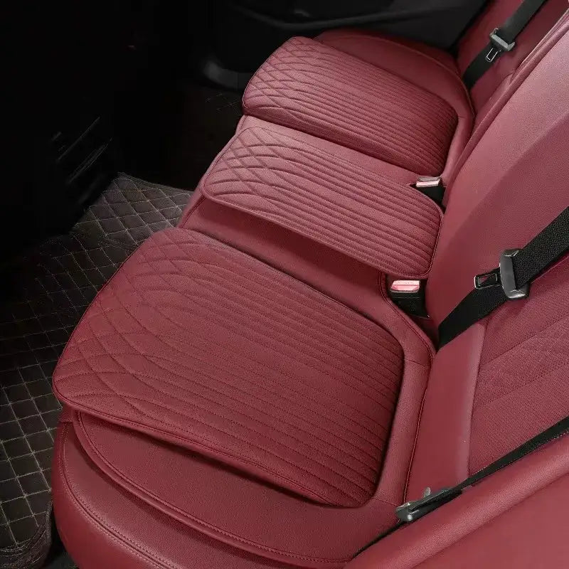 Red leather car seat height cushion installed on rear seat showing thick padded profile and perforated surface