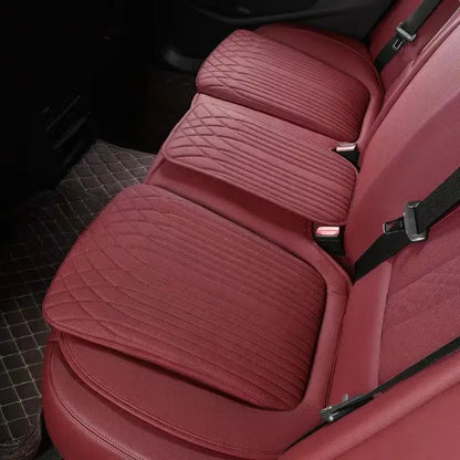 Red leather car seat height cushion installed on rear seat showing thick padded profile and perforated surface