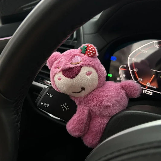 Pink plush bear toy clipped onto car turn signal lever as a cute dashboard decoration