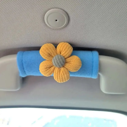 Blue plush car grab handle cover with yellow daisy flower decoration installed on car interior roof grab handle