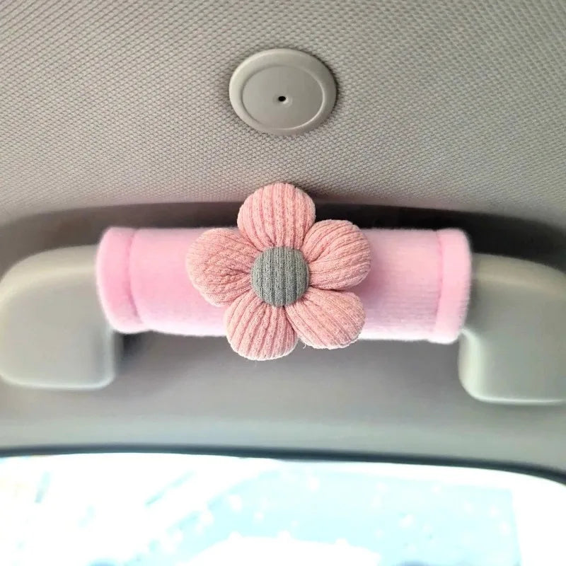 Pink plush car grab handle cover with pink daisy flower decoration installed on car interior roof grab handle