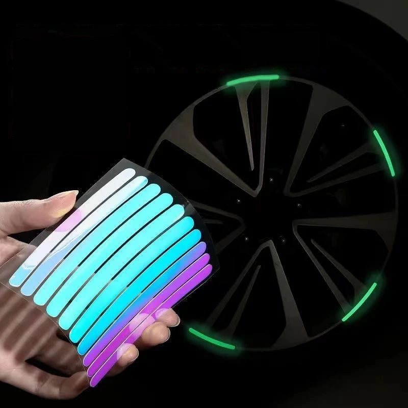 Hand holding colorful holographic rainbow reflective wheel rim tape strips next to car alloy wheel glowing green at night