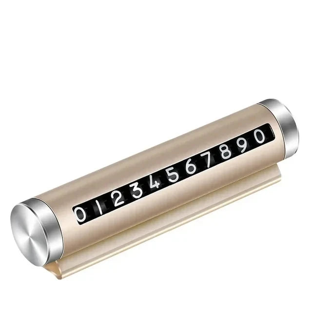 Gold metal rotating car parking number plate on white background showing full 0 to 9 digit roller and dashboard stand