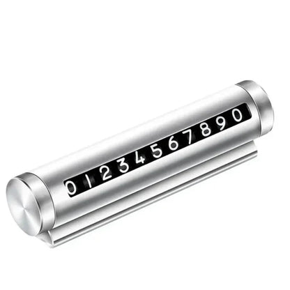 Silver metal rotating car parking number plate on white background showing full 0 to 9 digit roller and dashboard stand