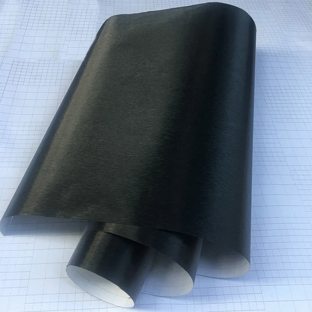 Black brushed aluminum vinyl wrap roll unrolled on grid background