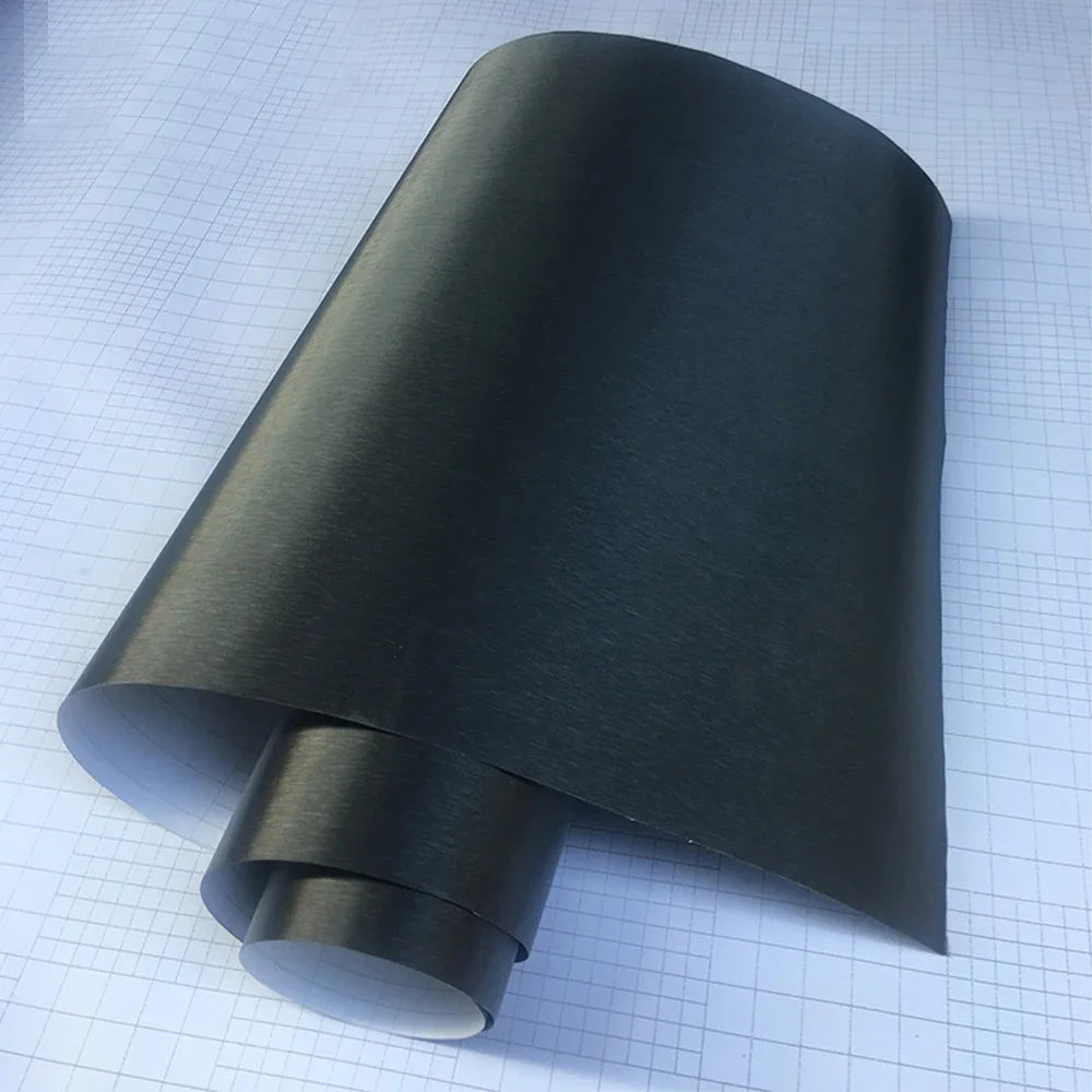 Deep grey brushed aluminum vinyl wrap roll unrolled on grid background