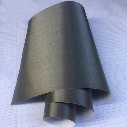 Grey brushed aluminum vinyl wrap roll unrolled on grid background