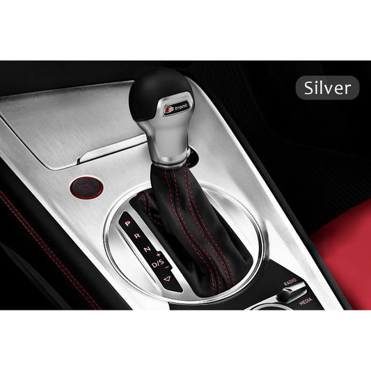 Silver gear shift cover with red-stitched leather on a brushed aluminum car interior trim