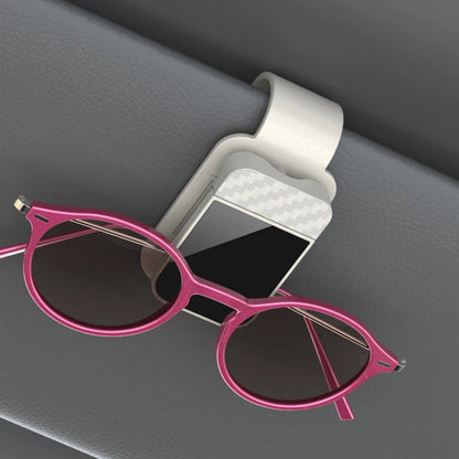 Beige sun visor glasses clip holding pink sunglasses on car interior
