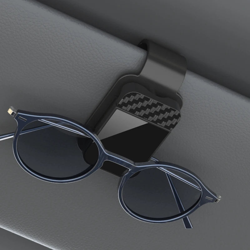 Black sun visor glasses clip holding blue sunglasses on car interior