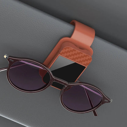 Brown sun visor glasses clip holding dark sunglasses on car interior