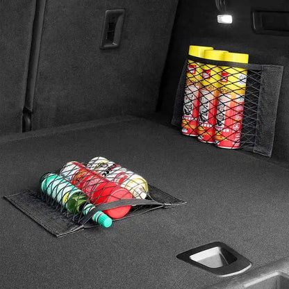 Two trunk cargo nets installed in dark car boot holding spray cans on wall and bottles on floor