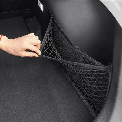 Hand spreading trunk cargo net flat across car boot floor showing full coverage