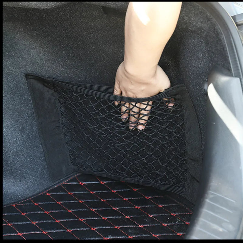 Hand pulling open trunk cargo net mounted on car boot side wall