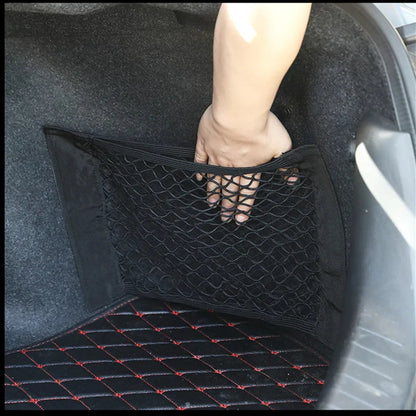 Hand pulling open trunk cargo net mounted on car boot side wall
